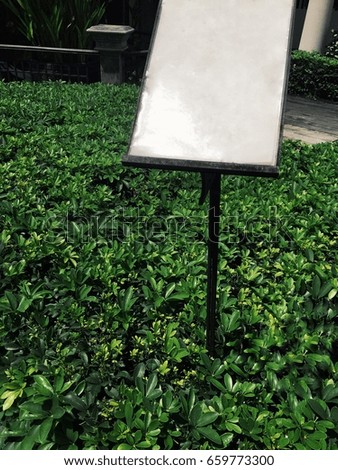 outdoor sign board, surrounded by the weed leaves in green background and chic garden