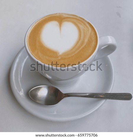 Hot coffee in white mug with heart-shaped drawing on top