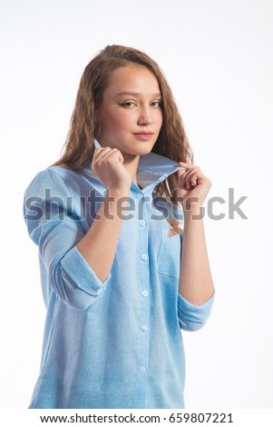 Portrait of a beautiful girl with long hair in a blue shirt on a white background