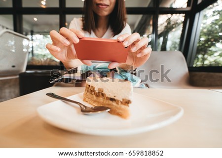 Hand of woman taking a photo of cake with smartphone.