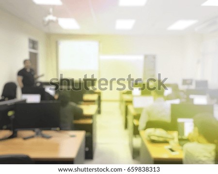 blurred image of student with teacher learning business technology desktop computer in a classroom and screen projector for present. education or training concept