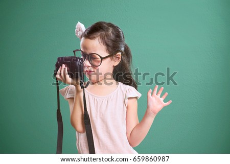 Little asian cute girl selfie with retro camera .  Vintage mint green wall background.