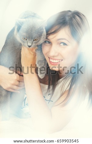 Beautiful girl with black hair playing with a gray cat  