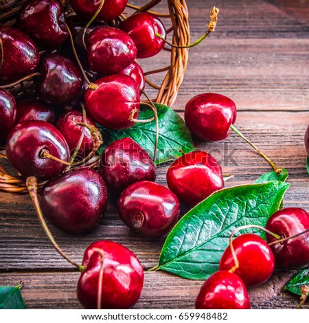 Cherries with leaves enough sleep from a basket on a wooden background
