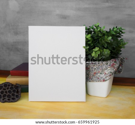 Mock up poster in a stylish interior. Blank empty canvas and decorative composition with books and a house plant.