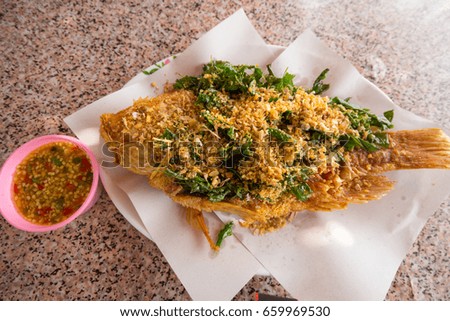 Fried fish with garlic on plat.