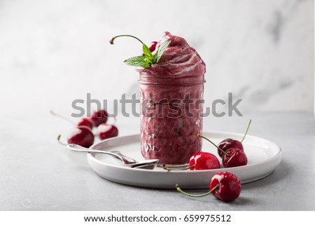 Sweet cherry and banana ice-cream in a jar on light background