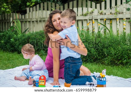 Happy mother and two children playing in summer garden