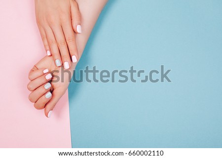 Stylish trendy female manicure. Beautiful young woman's hands on pink and blue background. Royalty-Free Stock Photo #660002110