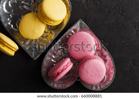 Closeup of yellow pink macaroons on black concrete background