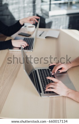 Close up shot of hands typing on keyboard of a laptop and a cup of coffee, notebook with pencil or pen.