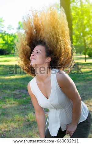 Happy beautiful young woman dancing in the park with trees in the background. European woman doing the dance of happiness. 