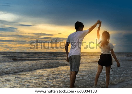 Young man and girl dancing at beach sunset