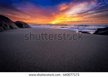 Deep blue tones of a breaking wave captured under a stunning sunset. A wave barreling onto a shallow reef under sunset light.