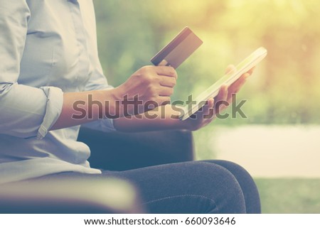 Young business woman hands holding a credit card and using tablet pc for online shopping. vintage tone