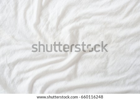Random abstract pattern of a white crumpled bed sheet in a hotel room. The manufacturing of bedsheet uses cotton, cotton blends, polyester and others fibers such as linen, silk modal and bamboo rayon.