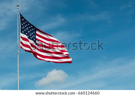 American Flag against the backdrop of a blue sky and clouds.  