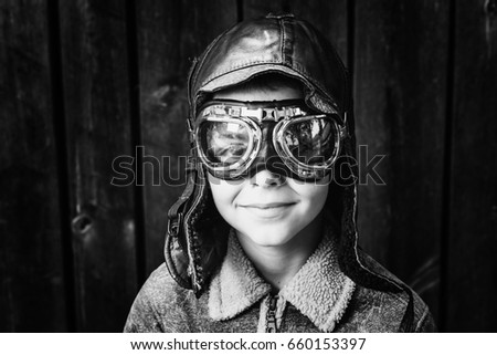 Boy dressed up in pilots outfit, jacket, hat and glasses,black and white photography