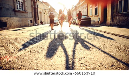 Group of young people with backpacks running through the street. Tourists concept. Exploring the city. Royalty-Free Stock Photo #660153910