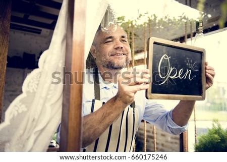 Man Hanging Open Sign by the Glass Window