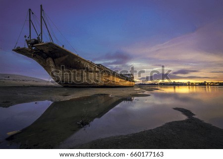stranded ship on side of river at sunset with blue sky