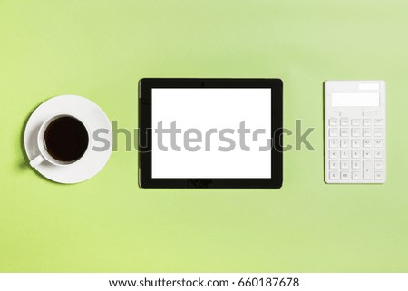 smart tablet with coffee, calculator on the green background.