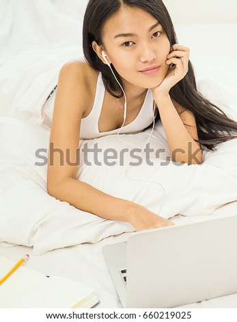 woman reading a modern computer tablet device while lying in bed happy and smiling