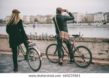 A couple enjoys bicycle ride on the Danube river embankment in Budapest, Hungary.  Toned picture