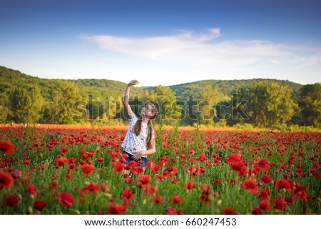 Summer scene of happy teen girl taking selfie with smartphone on the poppy field. Summer sunny day