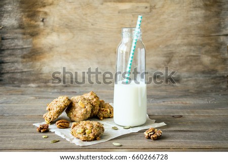 Fresh crispy traditional cookies with nuts and pumpkin seeds and a bottle of milk on a wooden table. Background of aged boards. Selective focus. Copy space