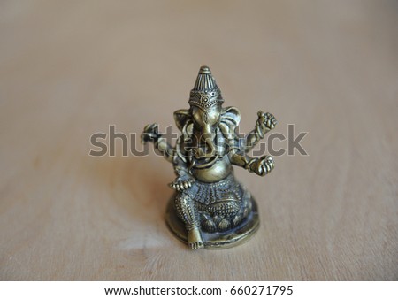 Ganesha's gilded figure on a light background