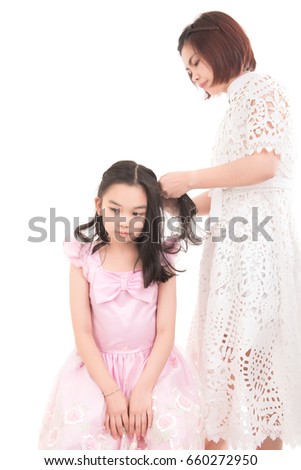 Portrait  of beautiful  mother is braiding hair of her daughter on white background, Cute little Thai girl with long hair, Asian girl braiding before go to school concept.