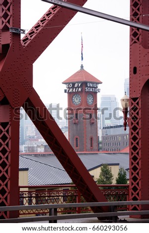 Tower of the train station in Portland with a clock and flag through the farms of Broadway Bridge on Willamette River