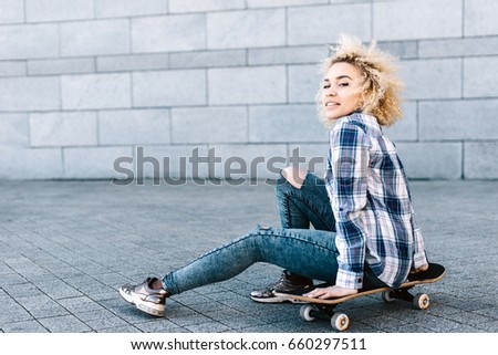 Attractive sports girl sitting on a skateboard