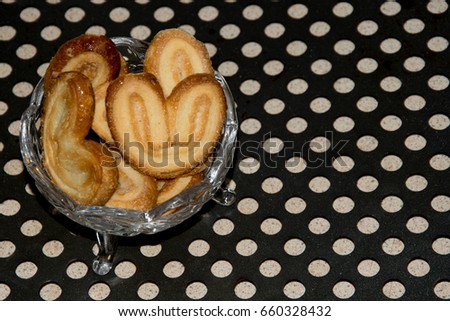 Puff pastry in a transparent glass vase on a black surface in holes