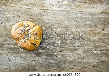 Top shot, close up of fresh baked homemade whole meal vegan loaf with raisin, decorated with seeds on a wooden, rustic table background, home baking, health care concept, white flour for decoration