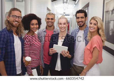 Portrait of smiling businesswoman team standing in corridor at creative office