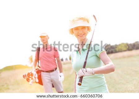 Portrait of happy female golfer with friend standing in background