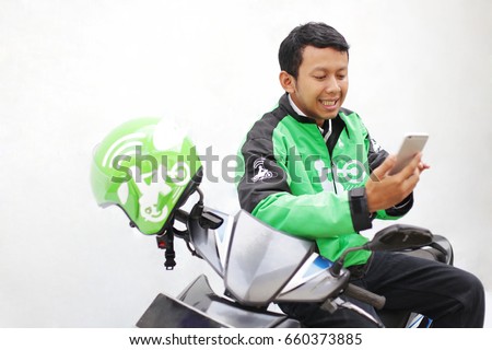 portrait man driver transportation motorcycle gojek, grab, uber touch mobile for order Royalty-Free Stock Photo #660373885