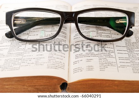 closeup of black glasses on dictionary background