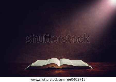 Light illuminating the Holy Bible on a wooded table. Royalty-Free Stock Photo #660402913