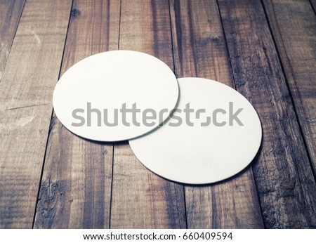 Two blank white beer coasters on vintage wooden table background. Responsive design mockup. Royalty-Free Stock Photo #660409594
