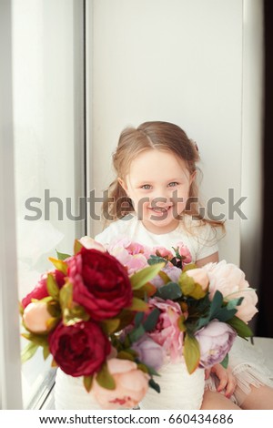 Small girl in colorful dress with flowers in hair. Facial expression.