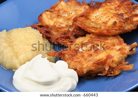 Delicious potato latkes for Hanukah, served on a plate with sour cream and applesauce.