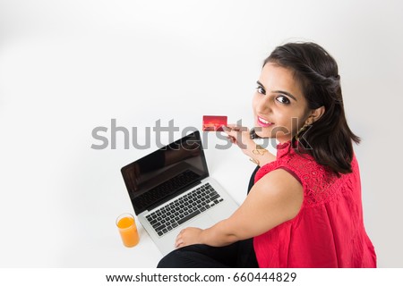 Digital India concept - beautiful looking indian young girl working on laptop and using debit/credit/ATM card for making payment online, sitting over white background