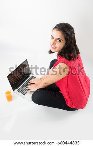 Digital India concept - beautiful looking indian young girl working on laptop and using debit/credit/ATM card for making payment online, sitting over white background