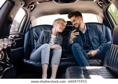 Business woman and business man having laugh in limousine
