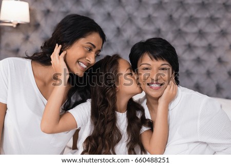 Girl loving mother and grandmother in bedroom at home