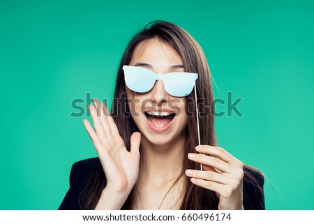 Happy woman, woman holding glasses on sticks on green holiday background.