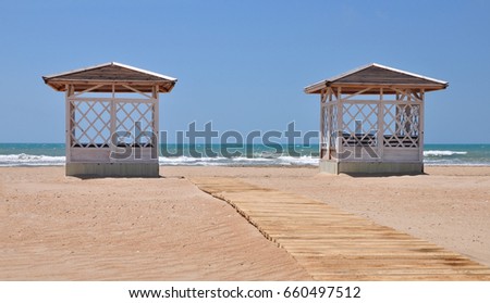 two wooden gazebos for relaxing on sandy beach near the sea